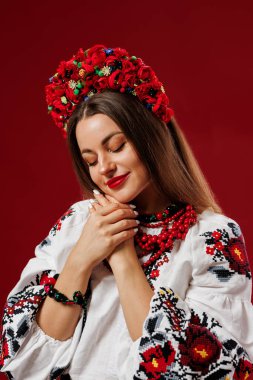 Portrait of ukrainian woman in traditional ethnic clothing and floral red wreath on viva magenta studio background. Ukrainian national embroidered dress call vyshyvanka. Pray for Ukraine