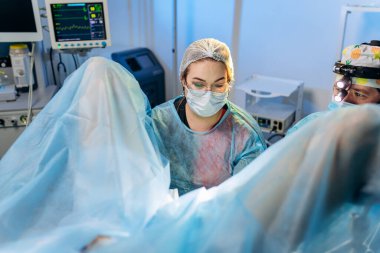 Profesyonel kadın cerrah proktolog hastanedeki ameliyathanede özel tıbbi aletler kullanarak ameliyat yapıyor. Acil cerrahi konsept