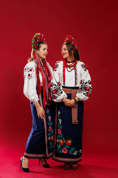 Ukrainian women in traditional ethnic clothing and floral red wreath on viva magenta studio background. National embroidered dress call vyshyvanka. Pray for Ukraine