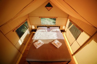 Gün batımında içi aydınlık, içi aydınlık, Cozy açık glamping çadırı. Yaz tatili ve tatil için lüks kamp çadırı. Yaşam tarzı kavramı