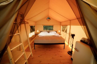 Gün batımında içi aydınlık, içi aydınlık, Cozy açık glamping çadırı. Yaz tatili ve tatil için lüks kamp çadırı. Yaşam tarzı kavramı