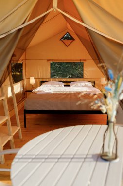 Gün batımında içi aydınlık, içi aydınlık, Cozy açık glamping çadırı. Yaz tatili ve tatil için lüks kamp çadırı. Yaşam tarzı kavramı