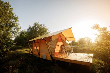 Gün batımında içinde ışık olan rahat, göz alıcı bir çadır. Yaz tatili ve tatil için lüks kamp çadırı. Yaşam tarzı kavramı