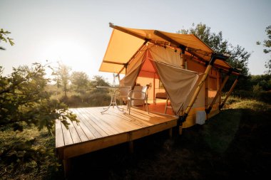 Gün batımında içinde ışık olan rahat, göz alıcı bir çadır. Yaz tatili ve tatil için lüks kamp çadırı. Yaşam tarzı kavramı