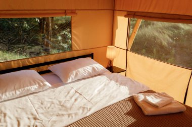 Gün batımında içi aydınlık, içi aydınlık, Cozy açık glamping çadırı. Yaz tatili ve tatil için lüks kamp çadırı. Yaşam tarzı kavramı