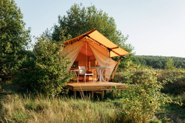 Gün batımında içinde ışık olan rahat, göz alıcı bir çadır. Yaz tatili ve tatil için lüks kamp çadırı. Yaşam tarzı kavramı