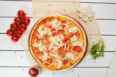 Füme tavuk filetosu ve ahşap zemin üzerinde domates, sos ve bitkilerle servis edilen gorgonzola peynirli taze pişmiş pizza. Yemek teslimatı konsepti. Restoran menüsü. Üst görünüm 