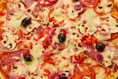 Taze pişmiş sosis, kırmızı biber, mantar, soğan ve zeytinli pizza ahşap zemin üzerinde domates, sos ve bitkilerle servis edilir. Yemek teslimatı konsepti. Restoran menüsü