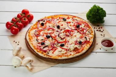 Domates, mantar, kırmızı biber, zeytin, soğan ve Mozzarella ile taze pişmiş vejetaryen pizzası ahşap arka planda sos ve otlarla servis ediliyor. Yemek teslimatı konsepti. Restoran menüsü