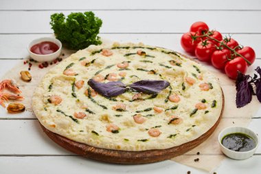 Karidesli taze pişmiş lezzetli pizza ve ahşap arka planda domates, sos ve bitkilerle servis edilen mozzarella peyniri. Yemek teslimatı konsepti. Restoran menüsü