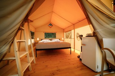 Gün batımında içi aydınlık, içi aydınlık, Cozy açık glamping çadırı. Yaz tatili ve tatil için lüks kamp çadırı. Yaşam tarzı kavramı