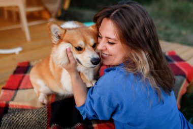 Galli Corgi Pembroke köpeği olan mutlu genç bir kadın yaz günü glamping yaparken dinleniyor. Açık hava eğlencesi ve dinlenme için lüks kamp çadırı. Yaşam tarzı kavramı