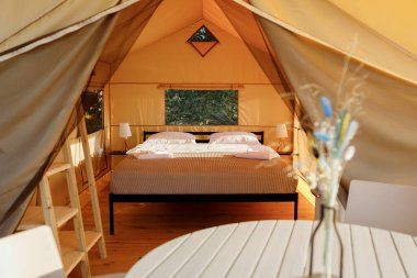 Gün batımında içi aydınlık, içi aydınlık, Cozy açık glamping çadırı. Yaz tatili ve tatil için lüks kamp çadırı. Yaşam tarzı kavramı
