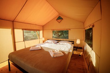 Gün batımında içi aydınlık, içi aydınlık, Cozy açık glamping çadırı. Yaz tatili ve tatil için lüks kamp çadırı. Yaşam tarzı kavramı