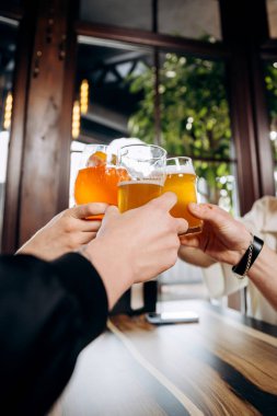 Arkadaşlar el kaldırır ve birlikte eğlenirler. Bar restoranında bira ve kokteyl içerler. Sosyal yaşam tarzı parti zamanı kavramı
