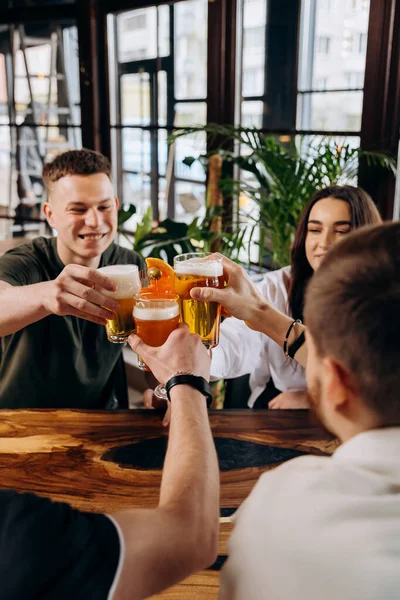 stock image Happy group of friends drinking and clinking with beer and cocktails at brewery bar restaurant. Beverage life style concept with guys and girls having fun together