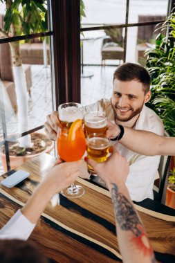 Bira ve kokteyllerle bira içen mutlu bir arkadaş grubu. İçecek yaşam tarzı konsepti. Erkekler ve kızlar birlikte eğleniyor.