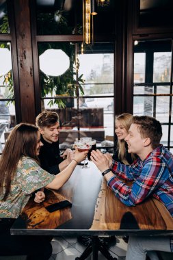 Bira ve kokteyllerle bira içen mutlu bir arkadaş grubu. İçecek yaşam tarzı konsepti. Erkekler ve kızlar birlikte eğleniyor.