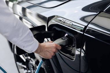 Vinnitsya, Ukrayna - 18 Mayıs 2023: BMW XM - Eklenti hibrid sistem sunumunda tam elektrikli edrive teknolojisi. Elektrikli araba sürücüsü şarj pillerine elektrik konnektörü yerleştirir
