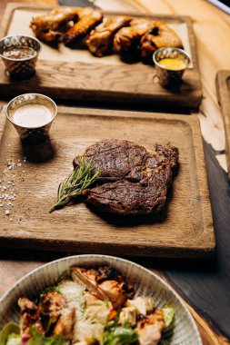 Tahta arka planda taze sulu lezzetli biftek. Baharatlı ve otlu et yemeği.