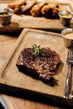 Tahta arka planda taze sulu lezzetli biftek. Baharatlı ve otlu et yemeği.
