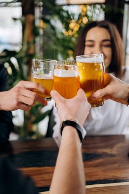 Arkadaşlar kadeh kaldırıyor ve birlikte eğleniyorlar. Bar restoranında bira içip kokteyl içiyorlar.