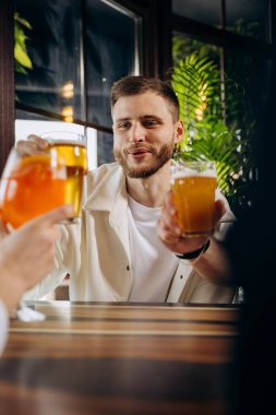 Arkadaşlar kadeh kaldırıyor ve birlikte eğleniyorlar. Bar restoranında bira içip kokteyl içiyorlar.