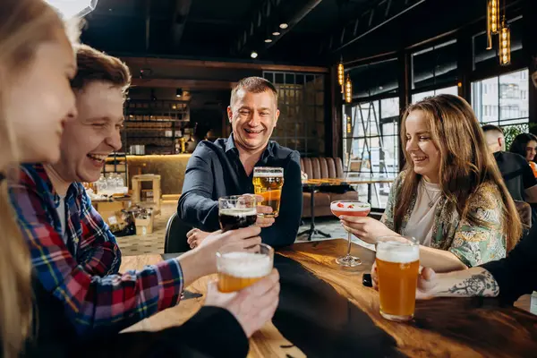 Group of happy friends drinking beer and and having talk in pub. Celebration and party concept