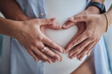 Karnını tutan hamile kadına yakın çekim. Çift yeni doğmuş bir bebeği bekliyor.