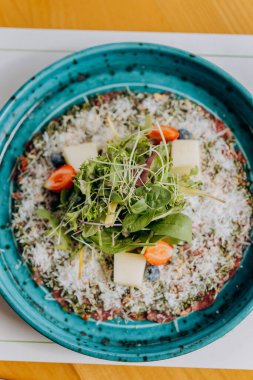 Pesto soslu sığır eti carpaccio ve salatayla süslenmiş parmesanlı peynir. Yüksek kalite fotoğraf