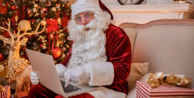 Noel Baba evde oturuyor ve dizüstü bilgisayarında yeni yıl dilek listesi ile e-posta okuyor.