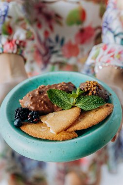 Çilekli bisküvilerle servis edilen çikolatalı tatlıyı tutan kadın elleri. Yüksek kalite fotoğraf