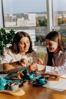 Gülümseyen bayan arkadaşlar kahve içer ve restoranda tatlı yerler. Yüksek kalite fotoğraf