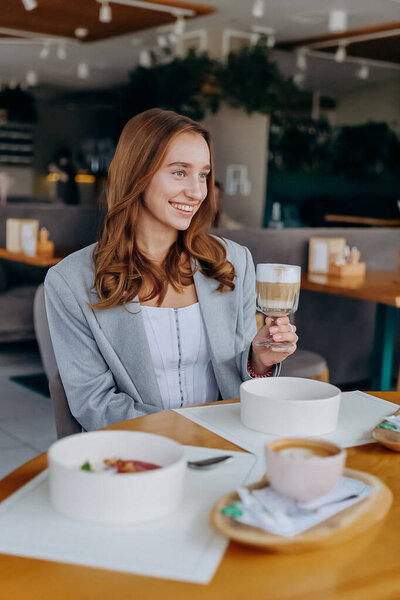 Young beautiful stylish woman drinking coffee while sitting in restaurant. High quality photo