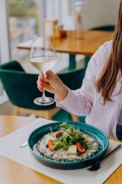 Gülümseyen kadın lezzetli yemekler yiyor ve restoranda şarap içiyor.