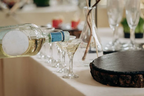 Waiter pouring martini in crystal glasses on table party at wedding reception