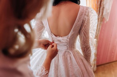 Gelinin özel gününe hazırlanırken gelinlik yakın plan, karmaşık dantel detaylarını gözler önüne seriyor. Yüksek kalite fotoğraf