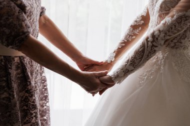 Bir anne ve gelinin el ele tutuşup düğün günü sevgiyi ve desteği yakaladığı dokunaklı bir an. Yüksek kalite fotoğraf