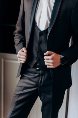 İş adamı ceketini düzeltiyor, profesyonelliği ve ofisteki detaylara dikkat etmeyi vurguluyor. Yüksek kalite fotoğraf