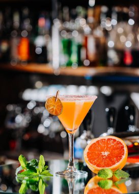 Close-up of vibrant orange cocktail garnished with dried citrus slice, perfect for summer