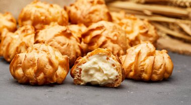 Lezzetli krema dolu profiteroller. Koyu bir sayfaya dizilmiş. Tatlı severler için mükemmel.