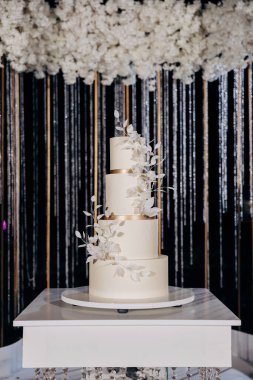Çiçek aksanlı, minimalist üç kademeli beyaz bir pasta ile zarif bir düğün hazırlığı. Gece gökyüzünün altında, yemyeşil beyaz çiçeklerle çevrili. Lüks etkinlikler ve zarif kutlamalar.
