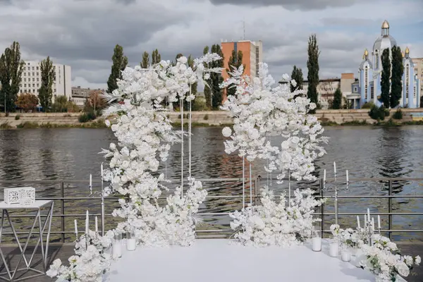 stock image Elegant outdoor wedding ceremony setup with white floral arrangements by the water. High quality photo