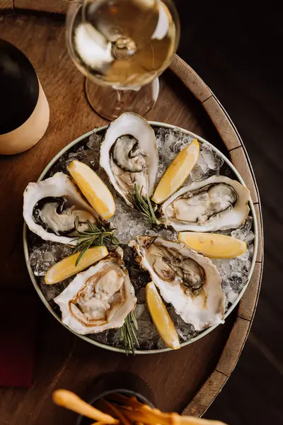 stock image Fresh oysters on ice with lemon wedges and white wine, ideal for gourmet dining and celebrations. High quality photo