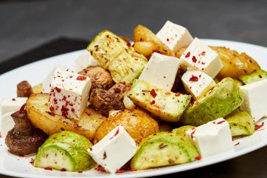 Feta peynirli kızarmış sebze salatası. Lezzetli bir ısırık için baharatlı otlar ve acı biber taneleri. Yüksek kalite fotoğraf
