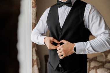 İş adamı yeleği ayarlıyor, profesyonelliği gösteriyor ve kurumsal ortamdaki detaylara dikkat ediyor. Yüksek kalite fotoğraf