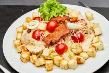 Fresh Caesar salad with cherry tomatoes, crispy bacon, and parmesan cheese, perfect for a light meal. High quality photo clipart