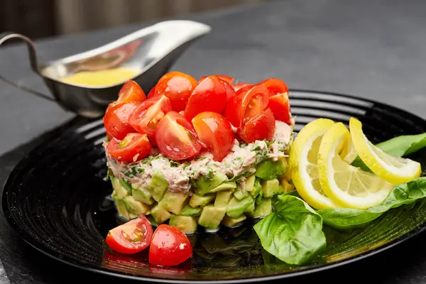 Çeri domatesli, limon dilimleri ve fesleğenle süslenmiş taze avokado ve ton balığı salatası. Yüksek kalite fotoğraf