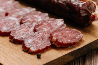 Tahta bir tahtanın üzerinde ince dilimlenmiş salam, zengin mermer ve gurme kalitesinde sergileniyor. Yüksek kalite fotoğraf