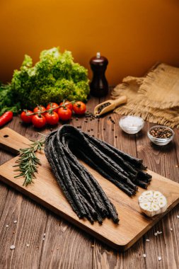Köy tahtasında tütsülenmiş et çubukları ve baharatlar, gurme yemek sunumları için ideal. Yüksek kalite fotoğraf